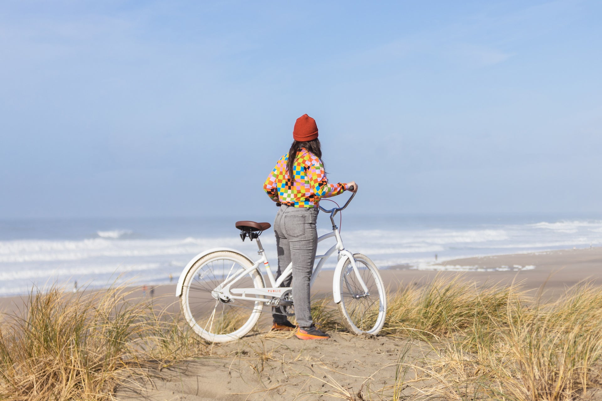 woman standing next to a beach cruiser bike by the sea